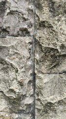 Close-up of rough stone wall texture with natural cracks and details. Perfect for use as a background, architectural design, construction material reference, or texture mapping in 3D and graphic proje