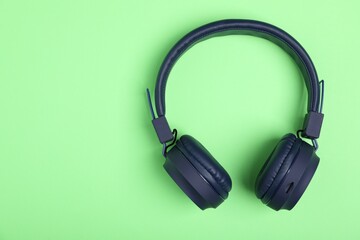 Pair of stylish blue headphones on light green background, top view. Space for text