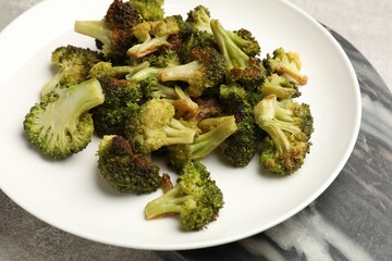 Tasty fried broccoli on light grey table, closeup