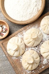 Uncooked khinkalis (dumplings) and spices on wooden table, flat lay