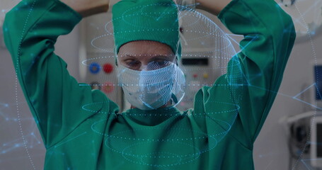 Surgeon in green scrubs and mask securing cap straps in operating room, with digital overlay
