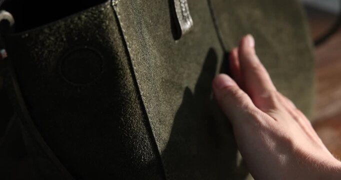 Woman touching olive leather bag indoors, closeup