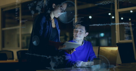 Colleagues wearing denim jacket reviewing on laptop and tablet in office at night, with overlays
