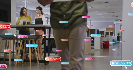 Walking man wearing green shirt khaki pants through open office space, with floating data labels