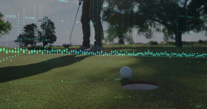 Golfer in sportswear analyzing white ball near cup at golf course green with putter, data overlay