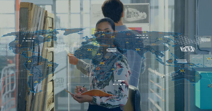 Designer in floral blouse holding notebook examining pinboard sketch in design studio with data map