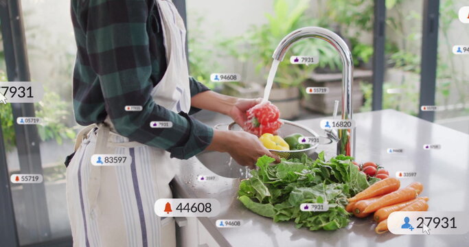 Washing woman wearing apron at counter, with red and yellow peppers under faucet icons, copy space - Powered by Adobe