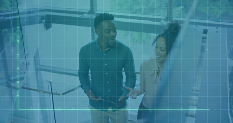 Discussing businessman and businesswoman gesturing toward glass whiteboard in office, with markers