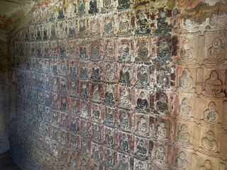 Thousand small Buddha relief on rock walls in Thousand-Buddha Grotto at Thousand-Buddha Cliff in Guangyuan, Sichuan, China, constructed from late Northern Wei Dynasty.