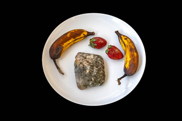 spoiled, old moldy food on white round plate in top view