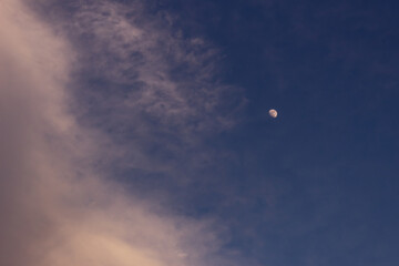 Moon and clouds in the blue sky at sunset, natural background.