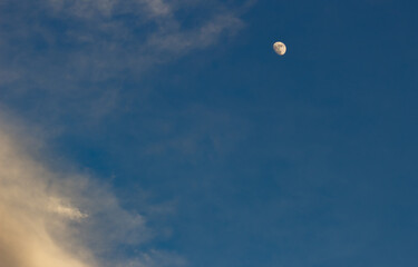 Moon and clouds in the blue sky at sunset, natural background.