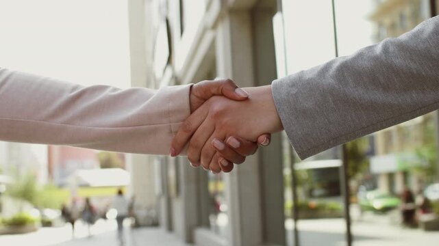 Women hands shaking over urban background. A Muslim woman interacts with others on a vibrant street in the city.