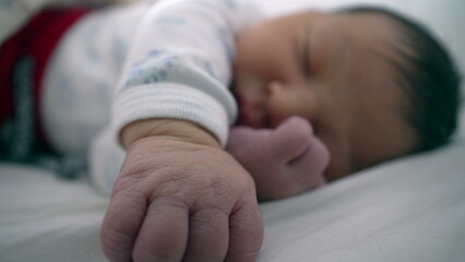 Newborn baby peacefully sleeping on a bed, with one hand extended and the other near the face. infant's calm expression and comfortable position highlight a moment of tranquility and security-SD 480p