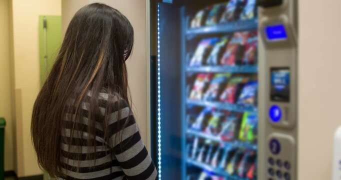 Female picking out snack selection at vending machine 4k