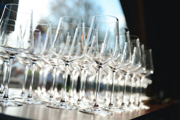 Stacks of empty champagne flutes with reflections and bokeh  luxury event preparation. © Andrew Avdeev