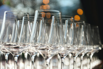Row of empty champagne flutes arranged for a reception; elegant glassware with soft bokeh.