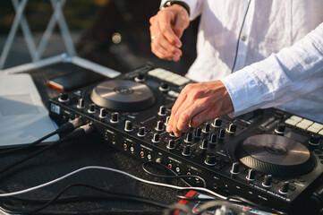 DJ hand adjusting knob on a professional controller at a party; electronic music mixing.