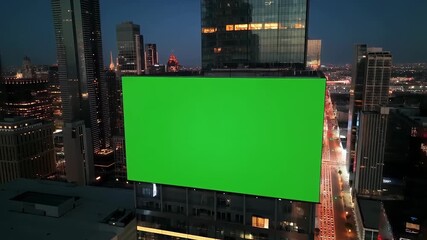 Dynamic Aerial Shot of a Modern City at Night Featuring a Large Green Screen Billboard on a Skyscraper. - Powered by Adobe
