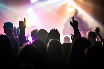 Adult Worshiping with Arms Raised in Room Lit with Stage Lighting
