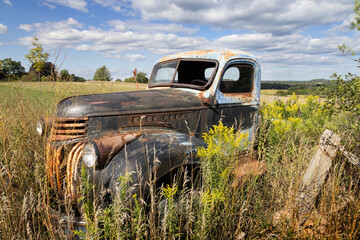 Rusty old pickup truck abandoned in a field exposed to the elements for decades