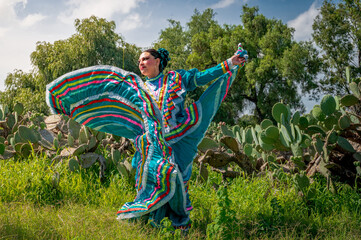 Traditional Mexican folkloric dancer with turquoise dress and cactus landscape