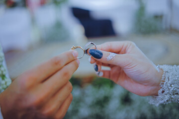 Close-up of a bride and groom holding wedding rings together, symbolizing love, unity, and eternal commitment in a meaningful marriage ceremony moment.