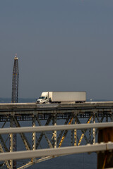 Obraz premium Truck driving across the bridge. Lorry transporting. Cargo trailer. Logistics truck, international shipment. Truck transport. Semi truck containers, logistics industry. Trucks lorry logistic concept.