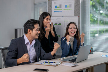 Three people are celebrating in a business setting
