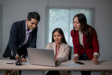 Three people are sitting at a desk with a laptop open