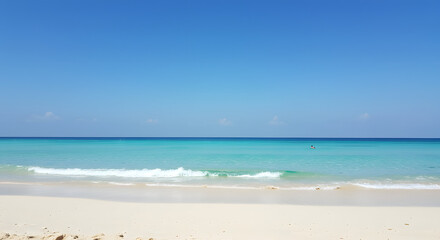 Obraz premium Serene turquoise ocean waves gently lap onto a pristine sandy beach under a clear blue sky.