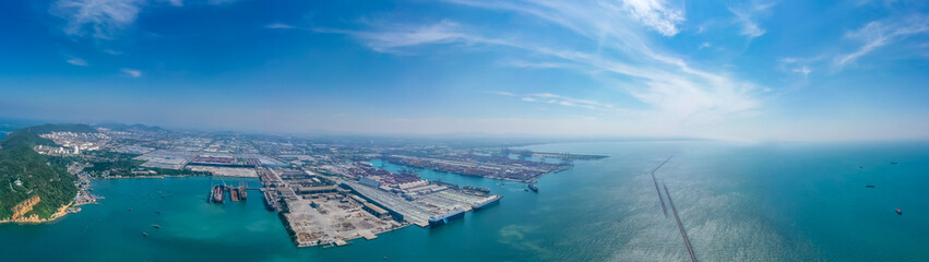 Fototapeta premium Aerial top view over international cargo ship at industrial import-export port prepare to load containers with big container loader ship vessel. global transportation and logistic business.