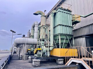 Fototapeta premium Industrial dust collector and air filtration system with large ducts and pipes, used for factory ventilation, pollution control, and air purification.