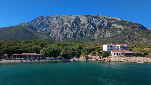 Drone view of Paralia beach with traditional Greek houses and the dramatic mountains of Samos