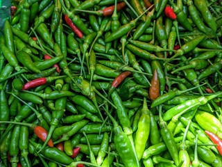 Full-frame shot of a pile of small green and red chilies. The image captures the texture and color variations, creating a lively and spicy food background