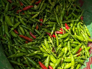 Full-frame shot of a pile of small green and red chilies. The image captures the texture and color variations, creating a lively and spicy food background