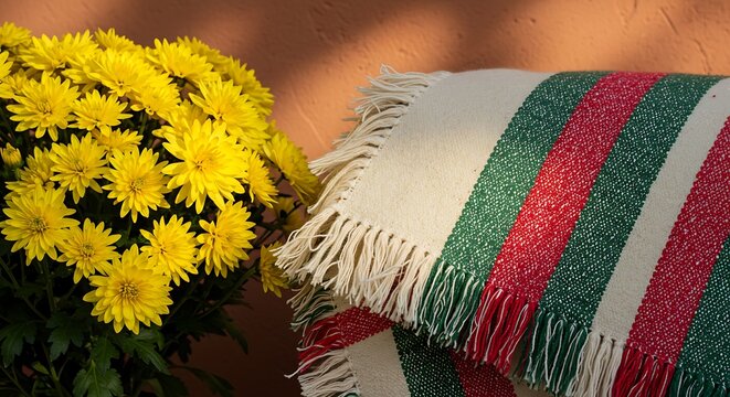 Bright yellow chrysanthemums next to a striped woven blanket with fringe yellow flowers - Powered by Adobe