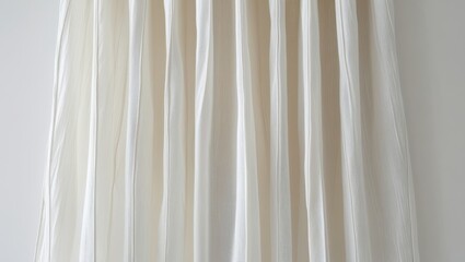 Obraz premium A soft, pleated, cream-colored fabric drapes elegantly in vertical folds against a neutral background.