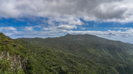 Beautiful mountain landscape. There are thickets of green forest on the mountainsides. Blue sky, clouds. Mauritius. Black River Gorges National Park. Gorges viewpoint