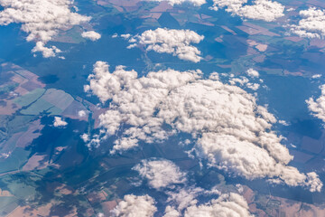 Aerial view from airplane window above green ground. View from the airplane window with beautiful clouds at sunrise © Dmitrii Potashkin