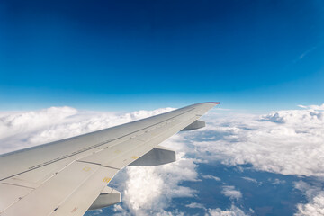 View from the airplane window at a beautiful cloudy sky and the airplane wing