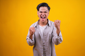 Fototapeta premium Happy Positive Excited Young Man Clenching Fists and Screaming, Celebrating His Victory or Success