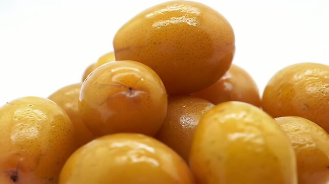 Close up of Shiny Yellow Jujube Fruits with Speckled Texture on White Background