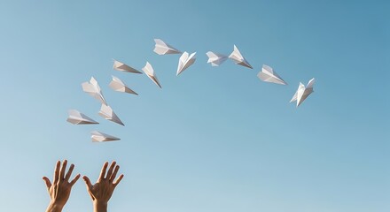 Fototapeta premium Hands releasing a series of white paper airplanes into a bright, clear, blue sky.