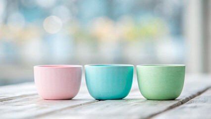 Three small pastel colored ceramic pots on a wooden surface pink blue