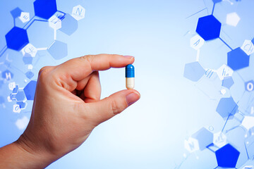 Hand holding blue white capsule with molecular structure background pill medicine