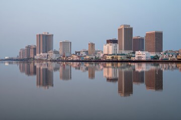 Obraz premium Serene Cityscape Reflection on Calm Water Under Soft Morning Light