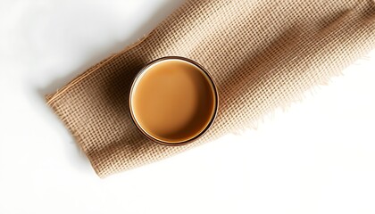 Glass of coffee with milk on a burlap cloth with frayed edges overhead view drink beverage