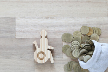 Man on wheelchair and coin money on wooden background,Save money for prepare in future and handicapped person concept