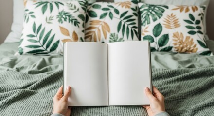 Person reading an open book on a bed surrounded by floral pillows